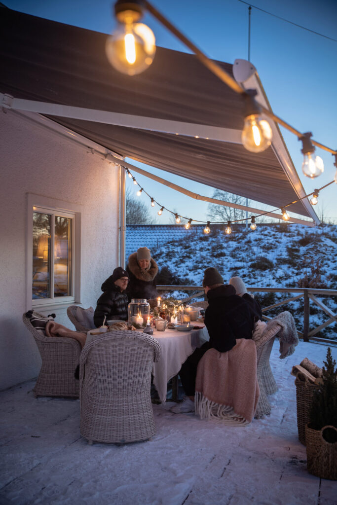 Fika under terrassmarkisen med skymningslandskap i vinterskrud