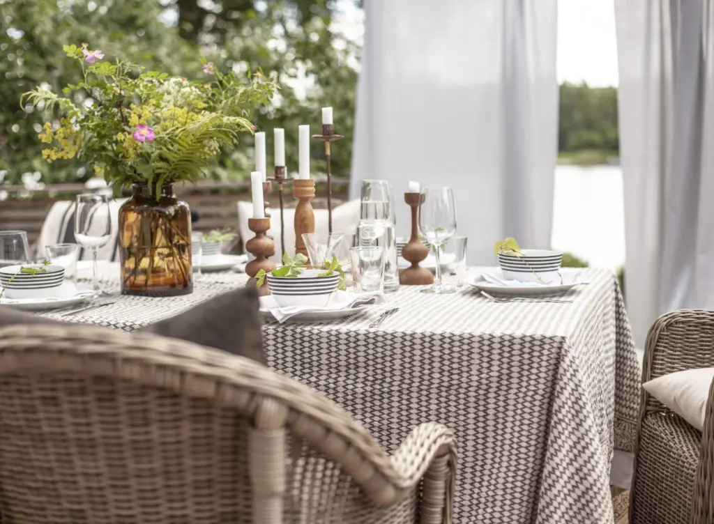 Dukat bord utomhus med vita gardiner i bakgrunden